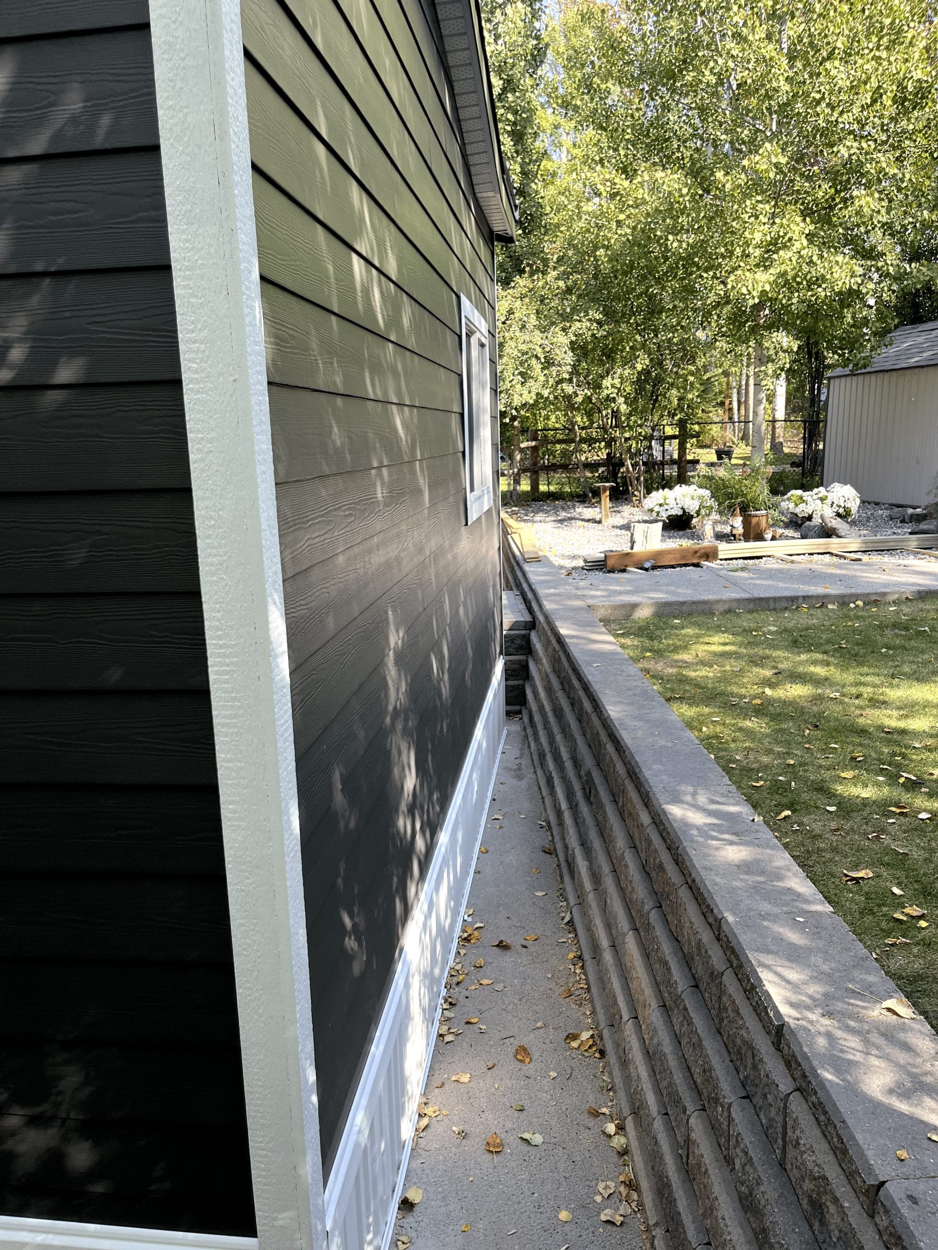Exterior of a HODA Construction project in Central Alberta with new siding, a stone retaining wall, and a landscaped yard